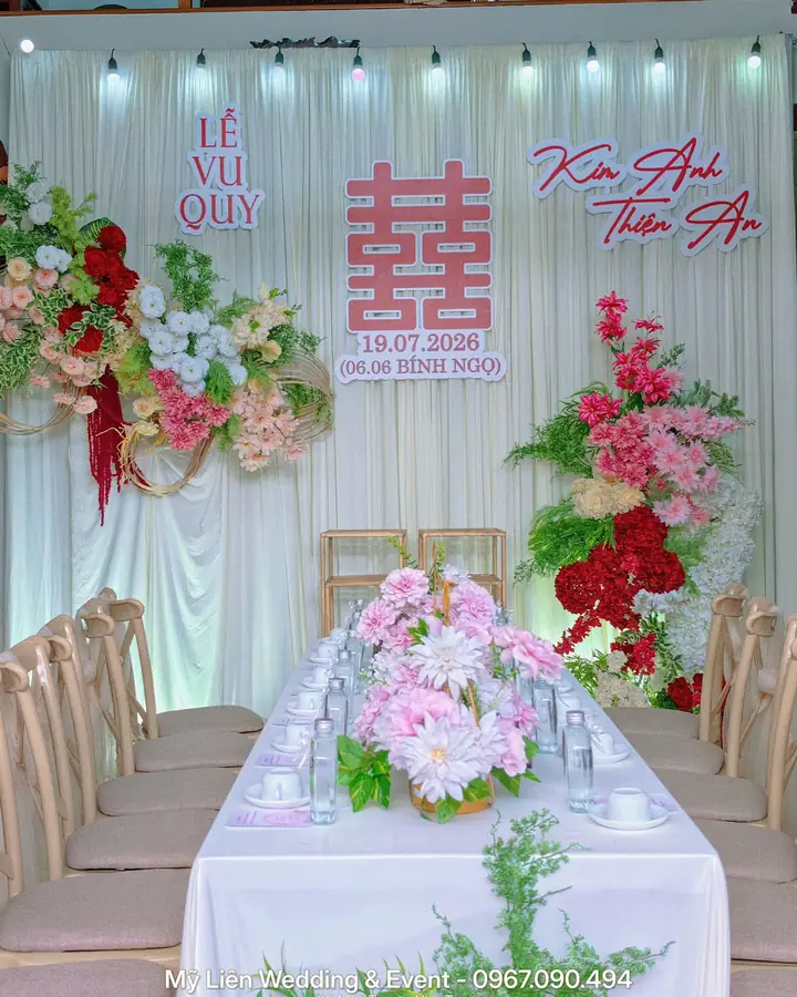 Bàn tiệc lễ vu quy với phông voan trắng, chữ hỷ đỏ và hoa lụa hồng, do Mỹ Liên trang trí